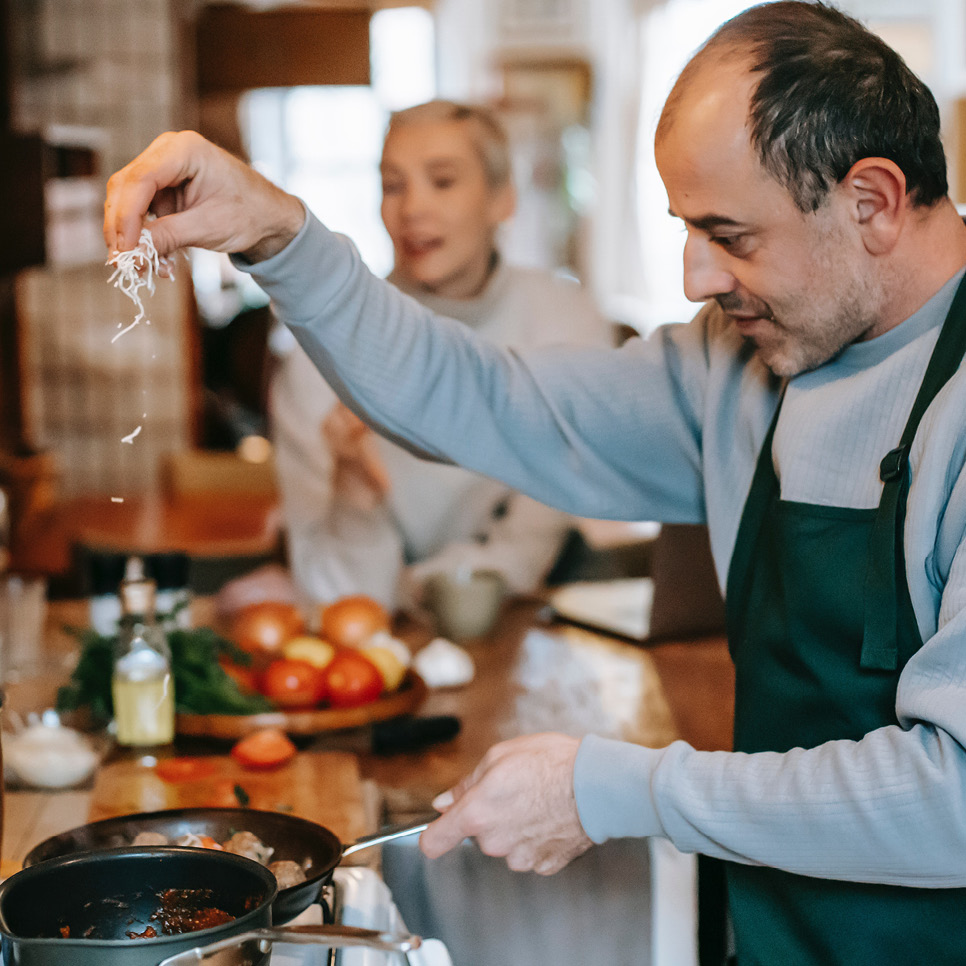 Ein Mann steht in der Küche und kocht mit der Familie zusammen